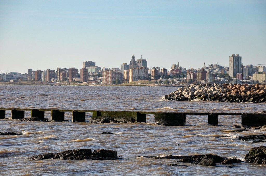 City skyline across the water with rocky shore