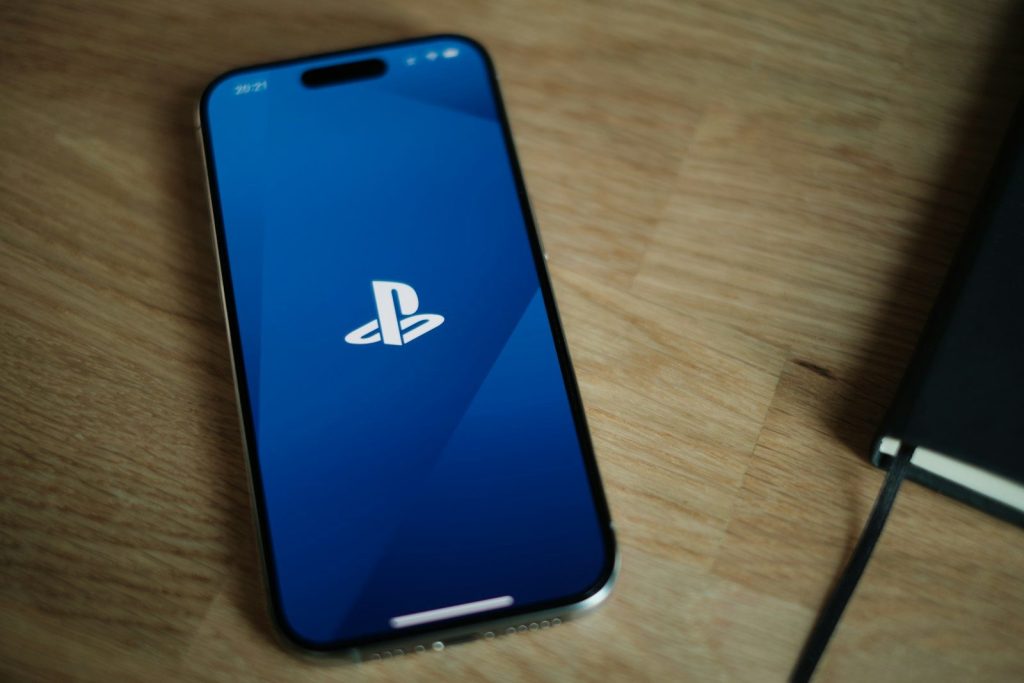 A sony phone sitting on a table next to a game controller