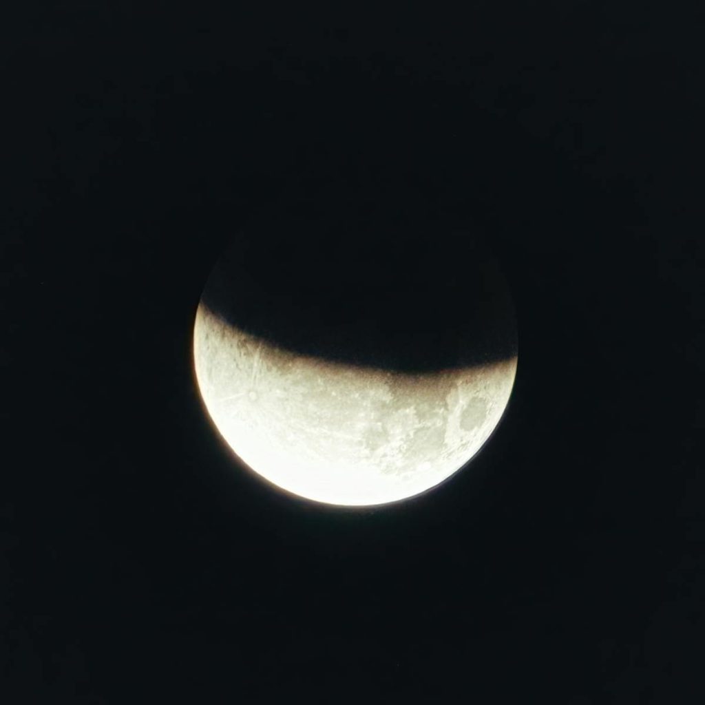 Stunning high-resolution photograph capturing a partial lunar eclipse and shadow play on the moon's surface.