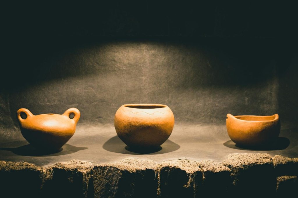 Elegant handcrafted clay jars presented under spotlight creating a warm, artistic feel.