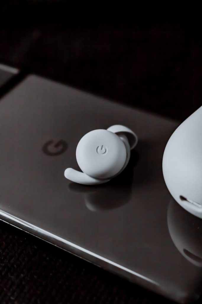 Close-up view of a wireless earbud on a smartphone, showcasing modern technology.
