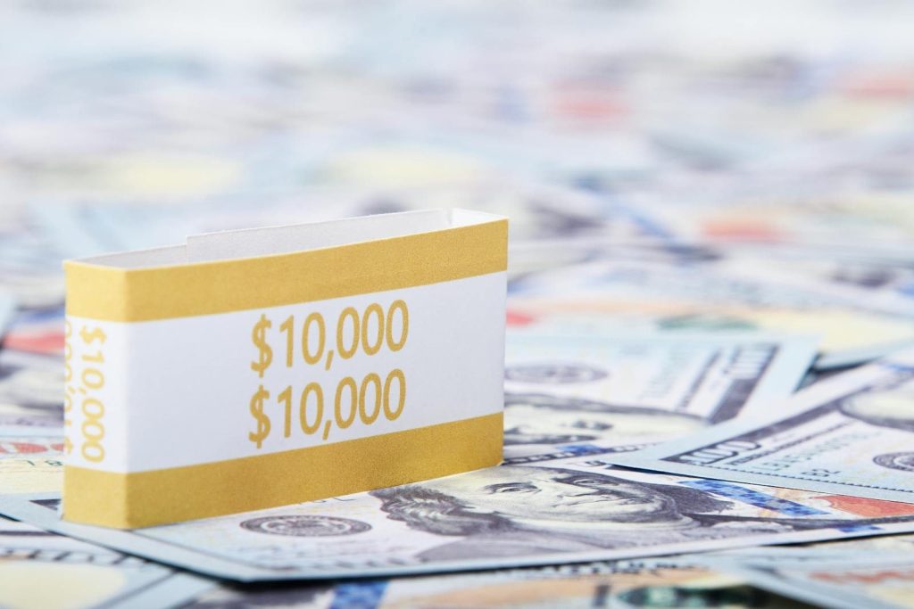 Close-up of a stack of $10,000 US dollar bills with a currency strap on a background of paper money.