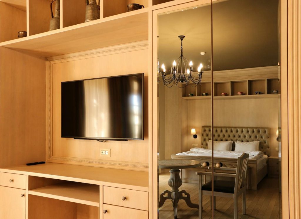 Luxurious hotel room featuring elegant furniture and a large mirror reflecting a chandelier.