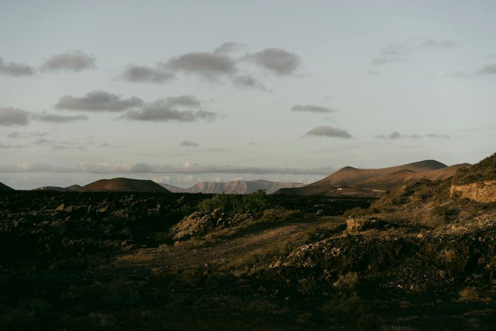 Peaceful arid landscape with hills and mountains under a dramatic sunrise sky.