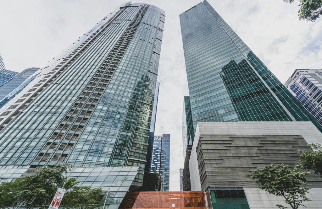 Low angle shot of towering glass skyscrapers reflecting a dynamic urban environment.