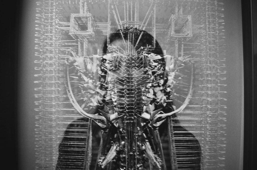 Black and white photo with double exposure of a woman and geometric glass reflections.