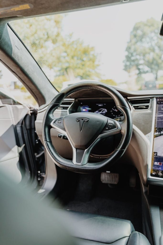 Modern Tesla car interior showcasing futuristic steering wheel design and high-tech dashboard.