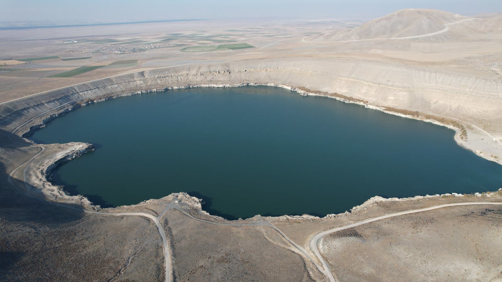 Drone shot of a barren crater lake surrounded by arid landscape in Turkey.