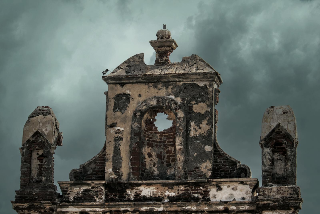 Weathered ruins of an old church facade set against a moody stormy sky.