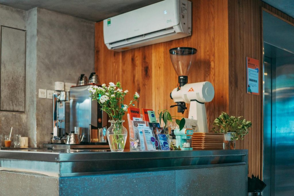 A modern coffee shop interior with wooden decor, stainless steel counter, and stylish appliances.