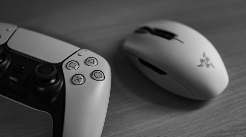 Monochrome image of a gaming controller and mouse on a desk, highlighting modern technology.
