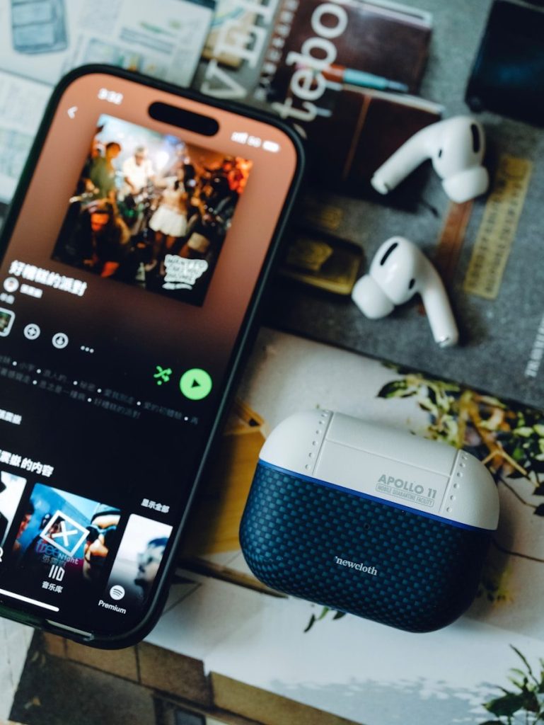 A smartphone playing music with wireless earbuds and a case.