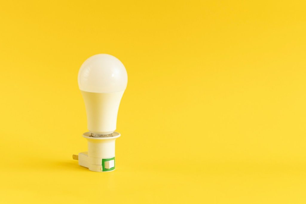 A white led light bulb on a yellow background