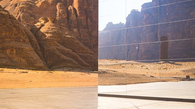 A vast desert landscape reflecting in sleek modern architectural glass.