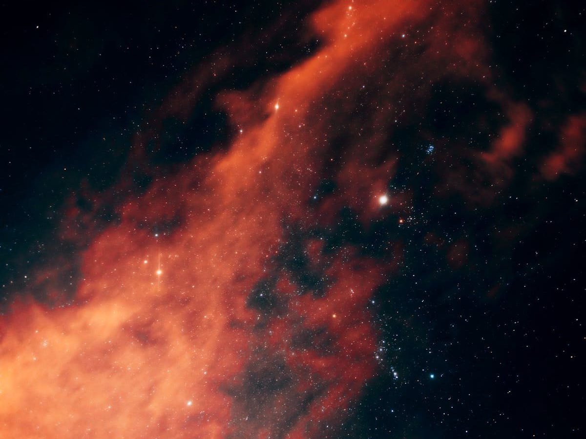 Vivid image of a red nebula with stars in the night sky creating a dramatic cosmic scene.