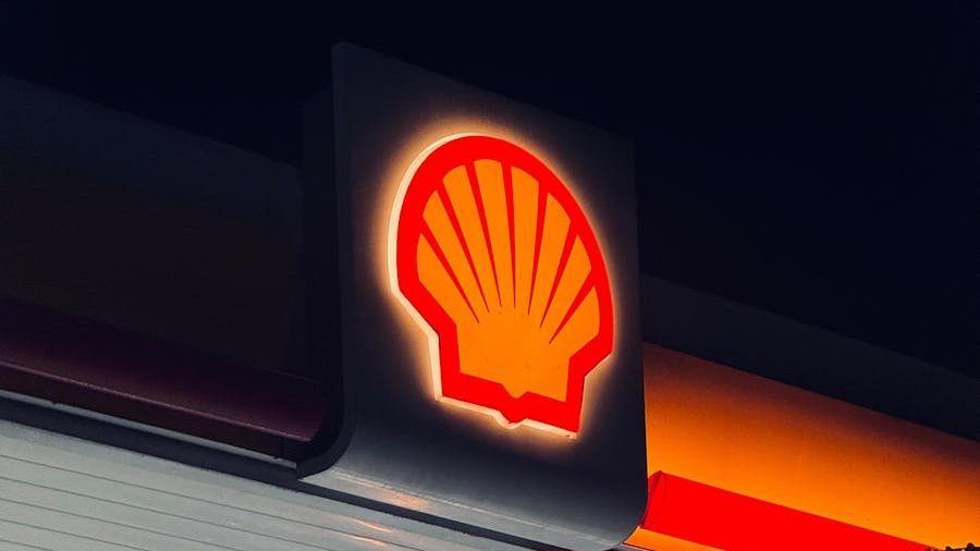 Illuminated Shell gas station sign captured at night in Bengaluru, India.