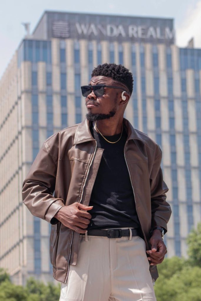 Fashion-forward man with sunglasses posing confidently outside the Wanda Realm building.