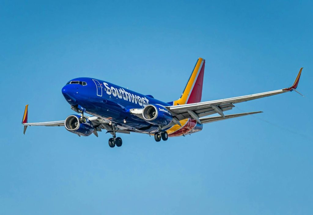 A Southwest Airlines Boeing 737 aircraft flying over Los Angeles, clear blue sky.