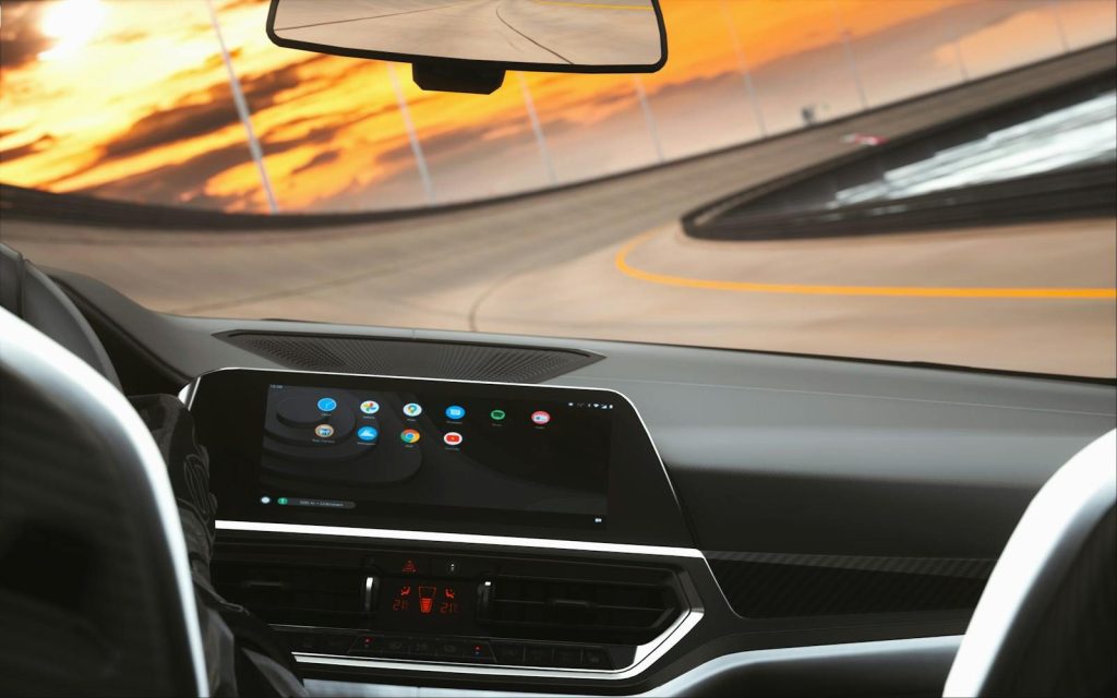 Sleek car interior featuring a digital dashboard during a sunset drive on a curved road.