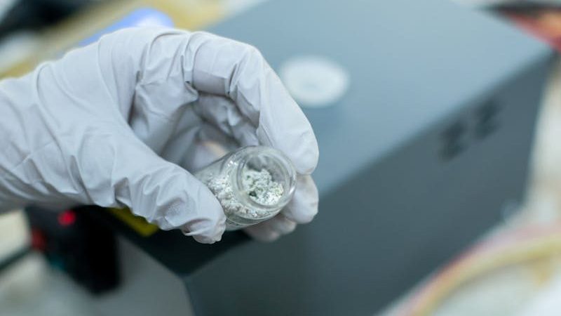 Close-up of a scientist handling metal samples in a laboratory experiment with precision tools.