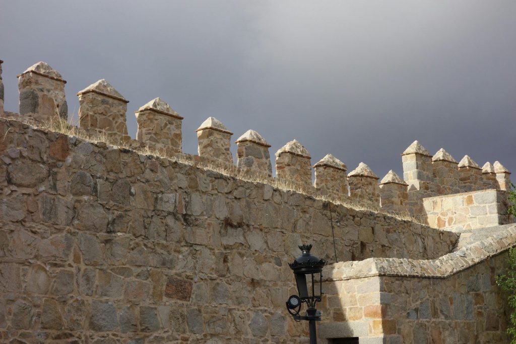 A stone wall with a lamp post in front of it