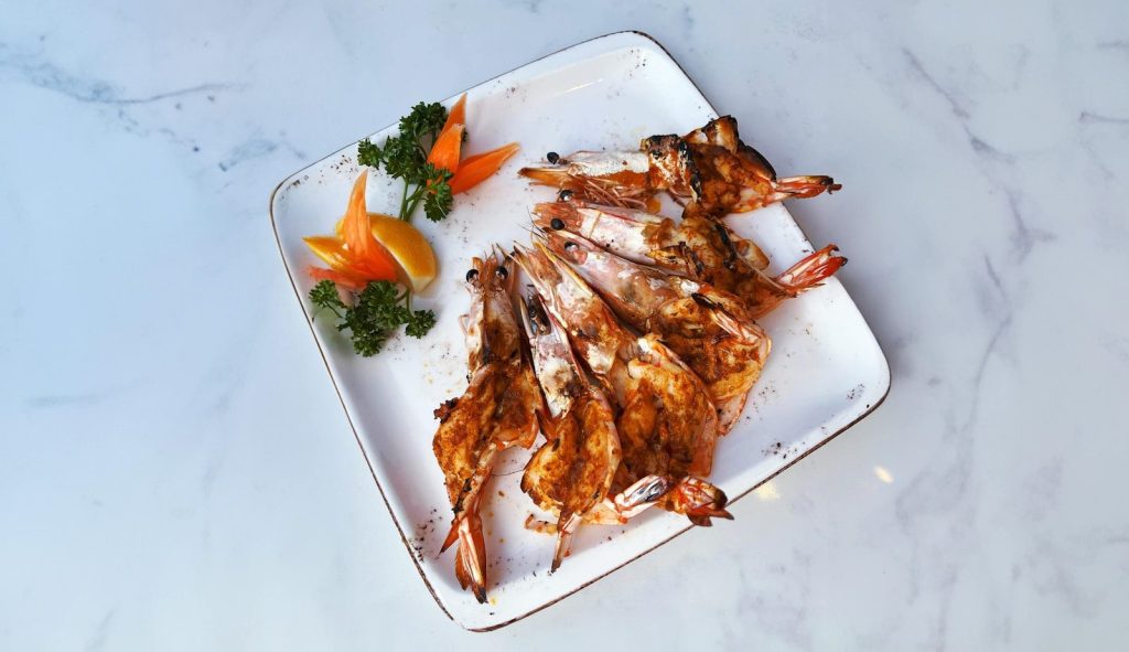 a white plate topped with grilled shrimp and veggies