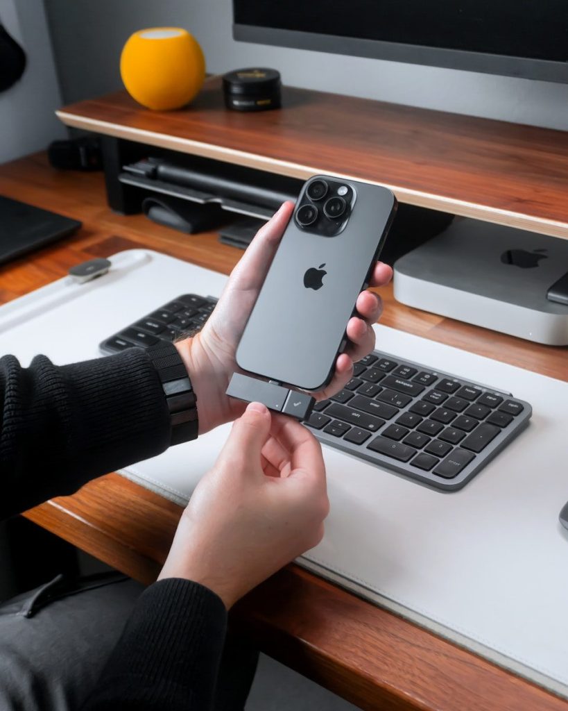 Hand holding iPhone with accessory on desk