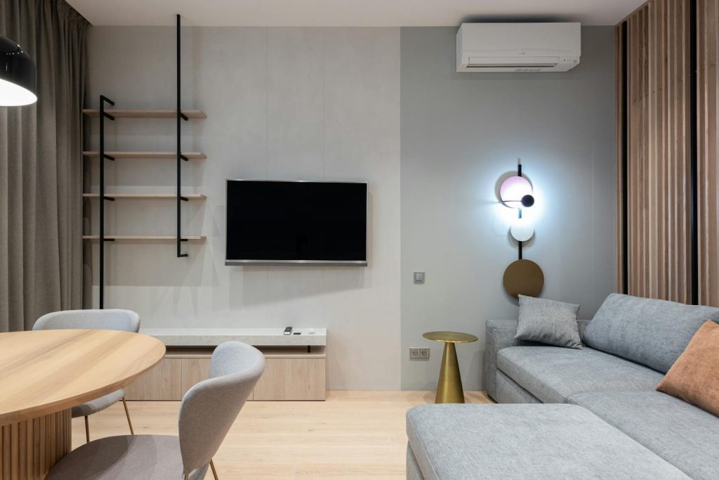 Comfortable living room furnished with big sofa placed near TV and shelf with curtains