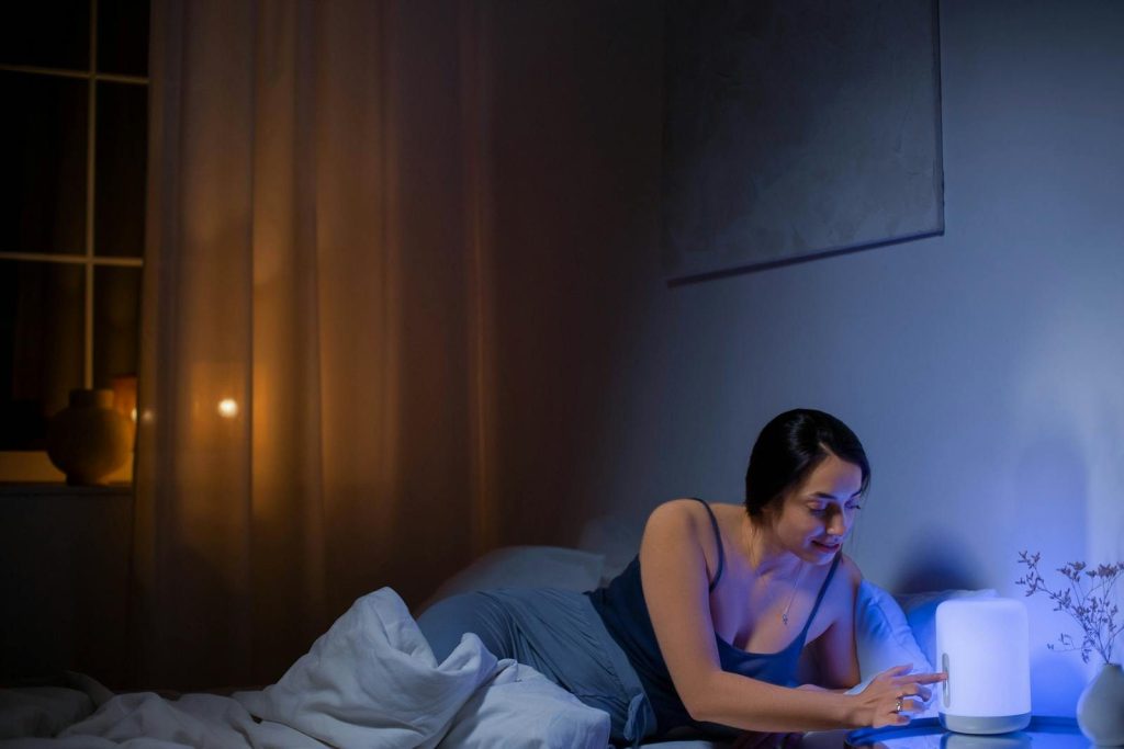 Young woman relaxing in her cozy bedroom at night with soothing ambient lighting.