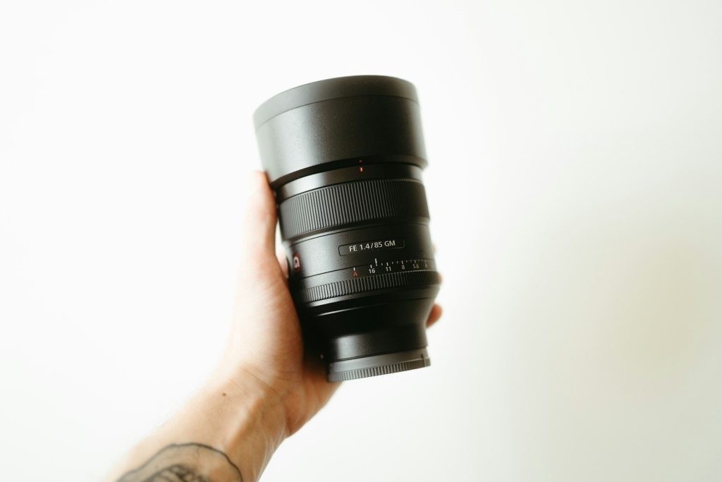 A hand holding a camera lens.