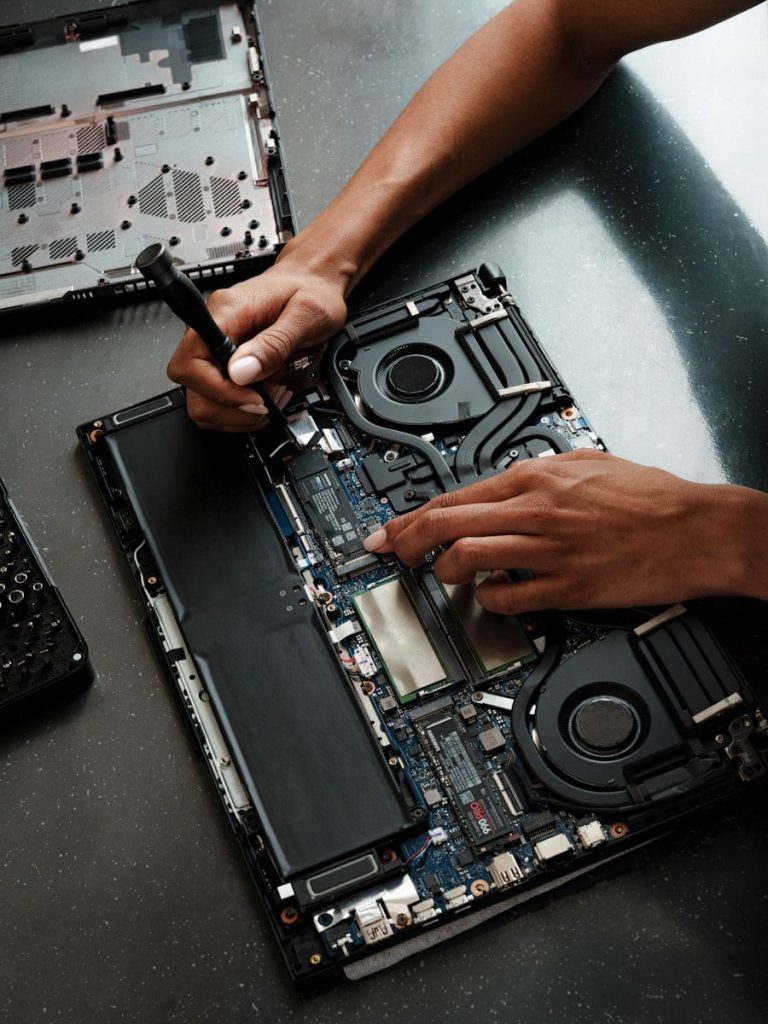 A person working on a laptop with a screwdriver