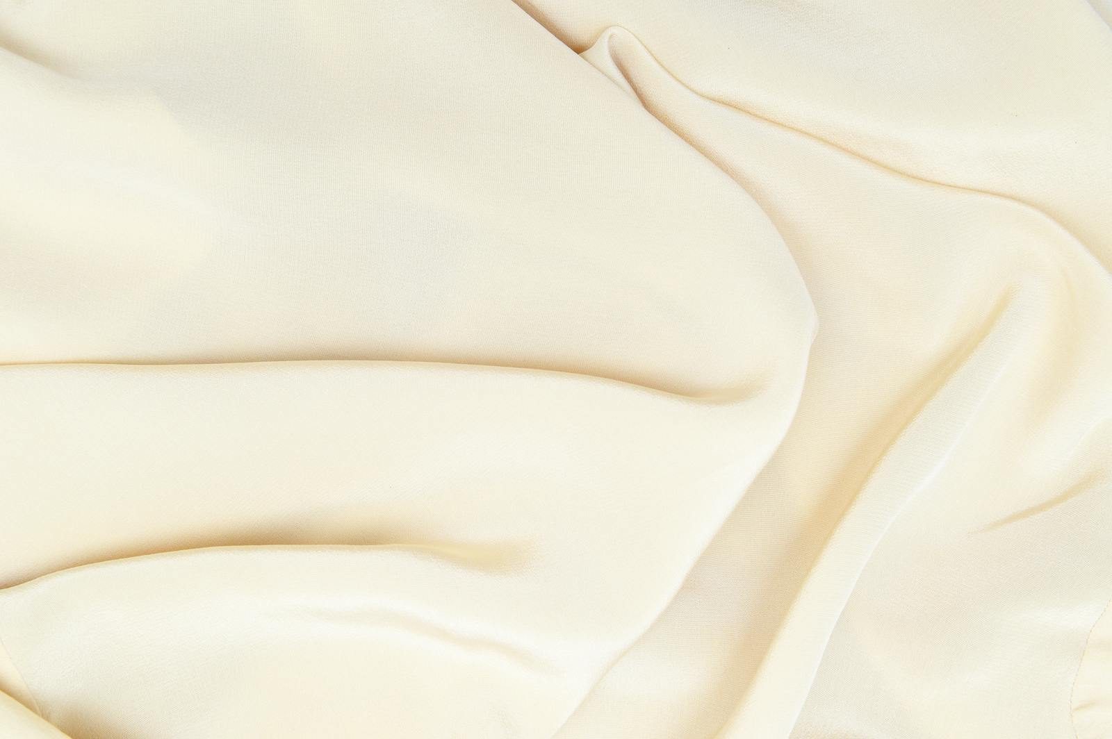 Close-up of cream silk fabric showcasing smooth texture and gentle folds.