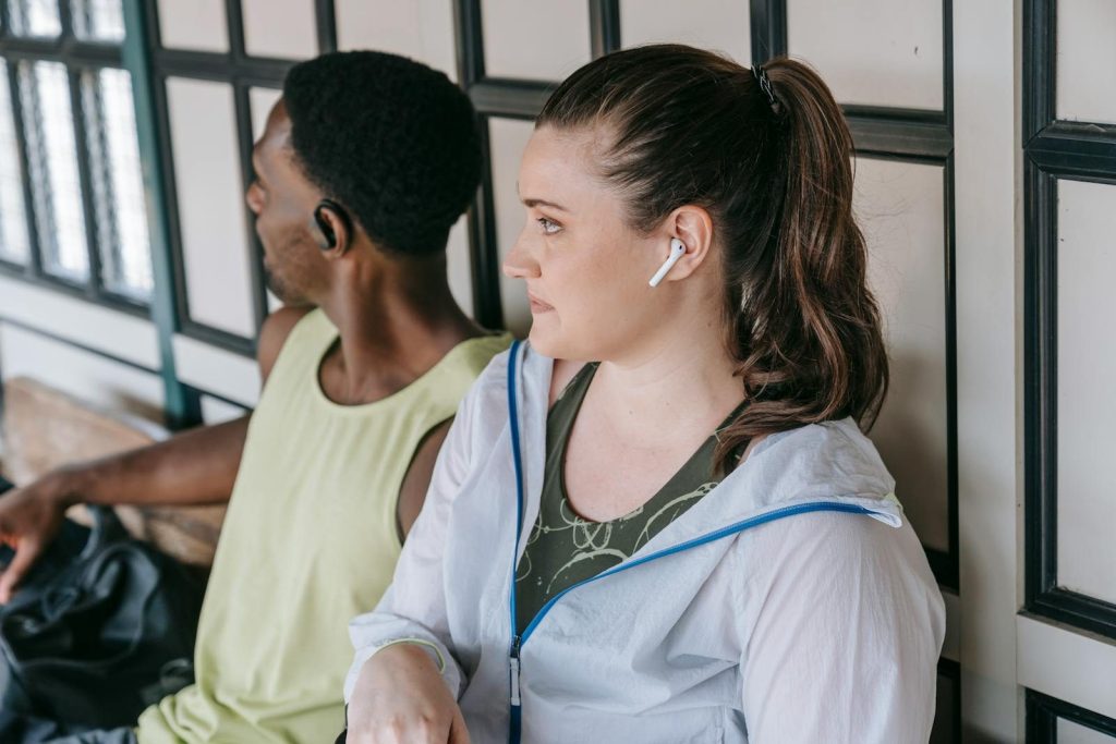Casual interaction between friends wearing earbuds indoors, focused on technology and relaxation.