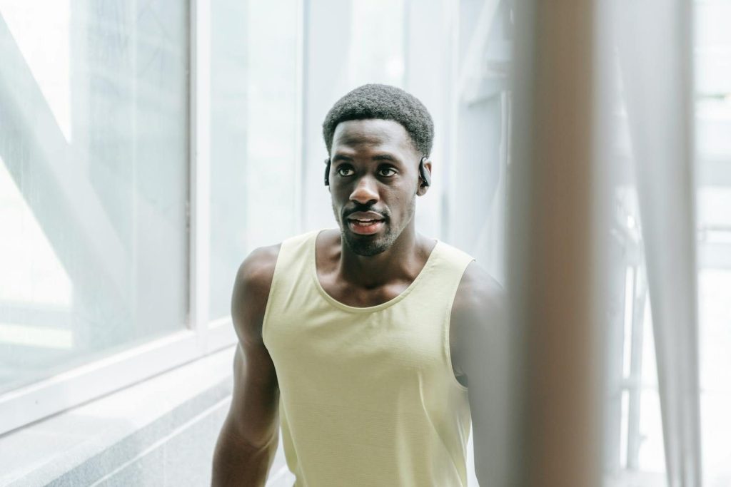 Young man walking in a modern indoor setting wearing a tank top and exercising.