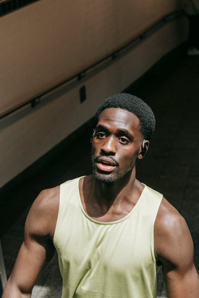 A fit African American man in a tank top, captured in an urban setting, exuding strength and confidence.