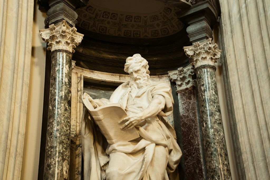 Marble statue of a man reading a book.