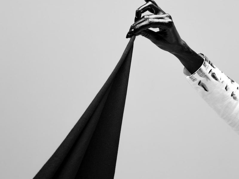 grayscale photo of man in black robe holding black umbrella