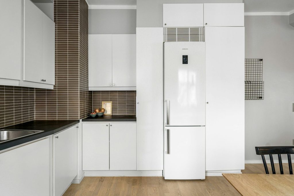 A kitchen with white cabinets and wooden floors