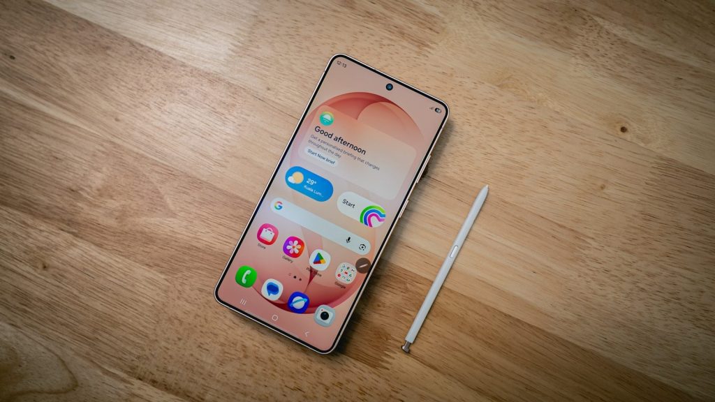 A smartphone with a stylus rests on a wooden surface.