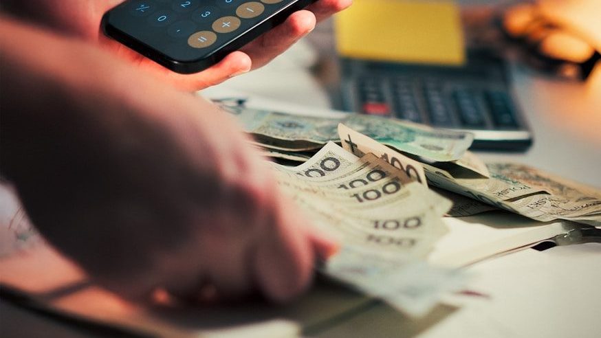 Hands holding money and using calculator on phone.