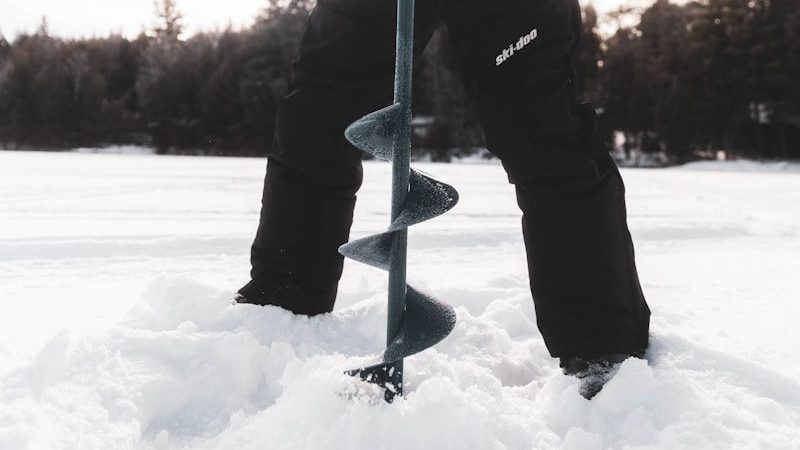 man in black jacket and black pants holding black smartphone on snow covered ground during daytime