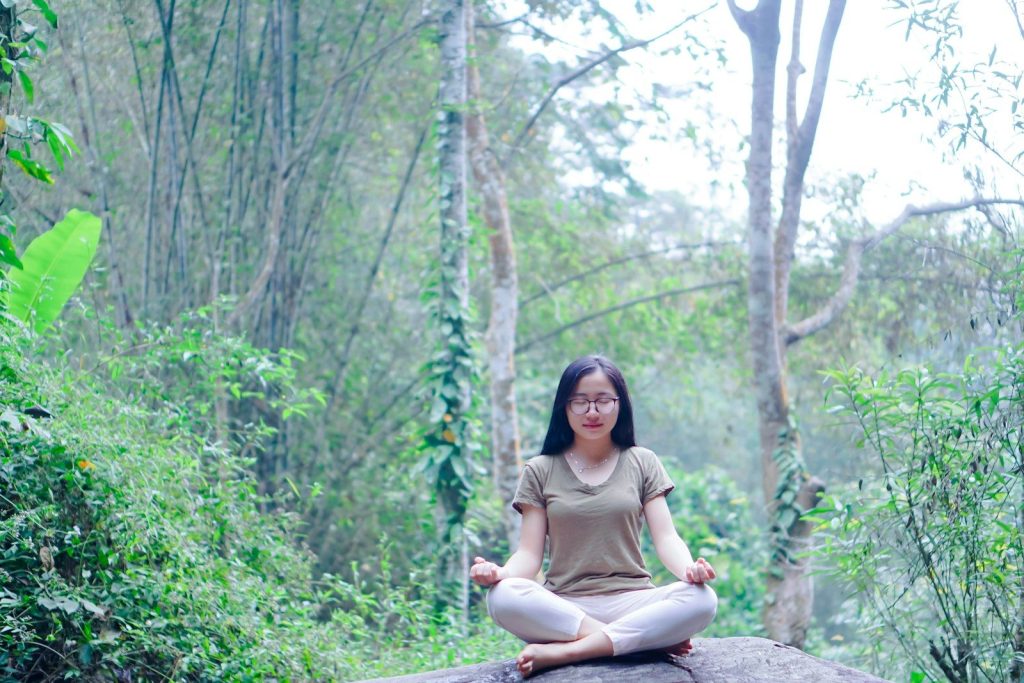 a woman sitting on top of a rock in a forest
