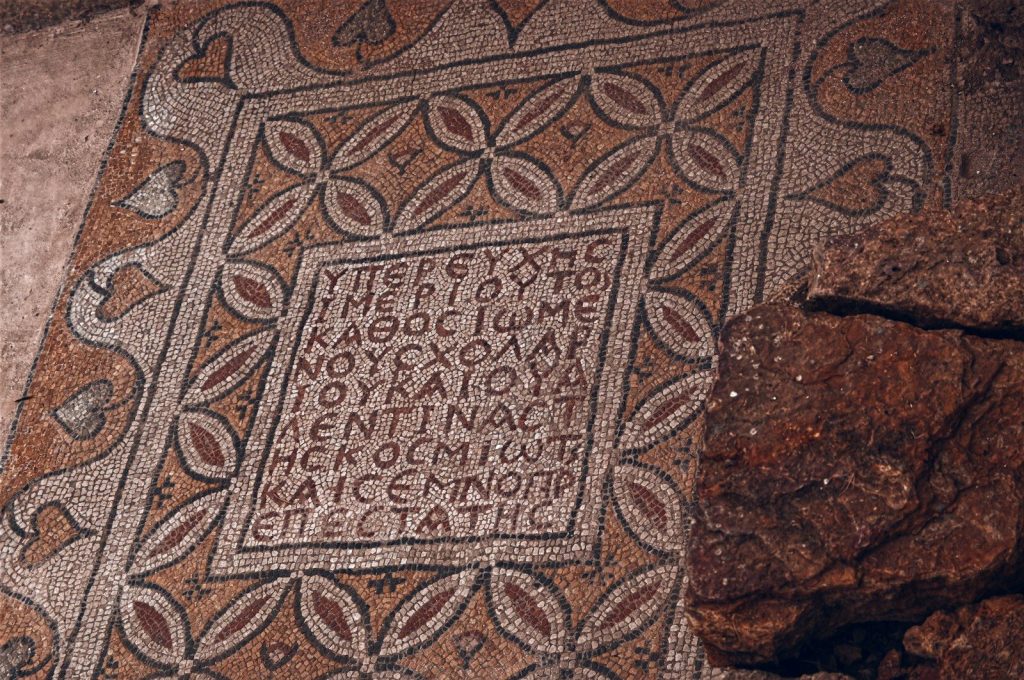Ancient mosaic with greek inscription and floral pattern