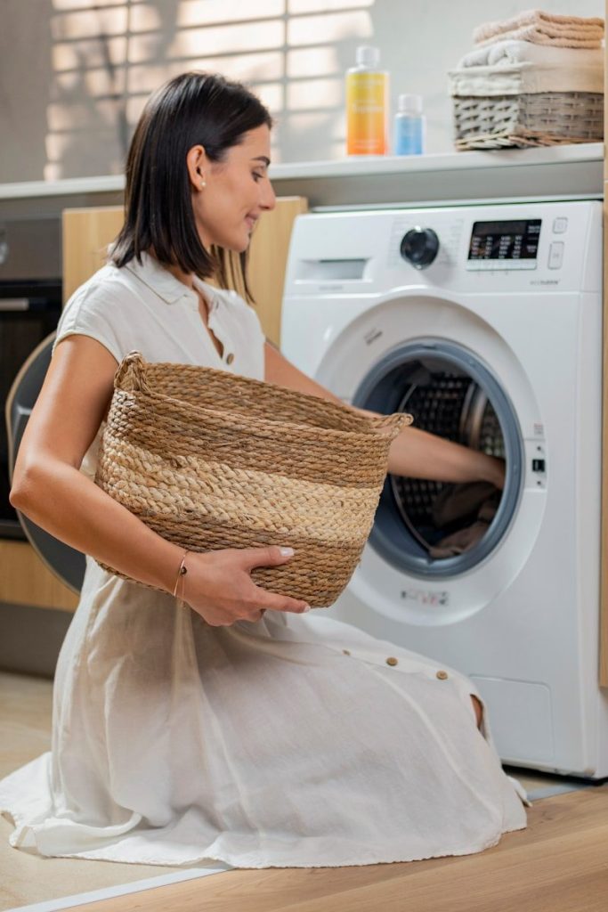 a woman holding a basket in front of a washing machine