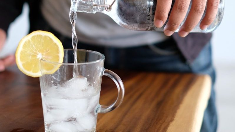 man pouring water in glass