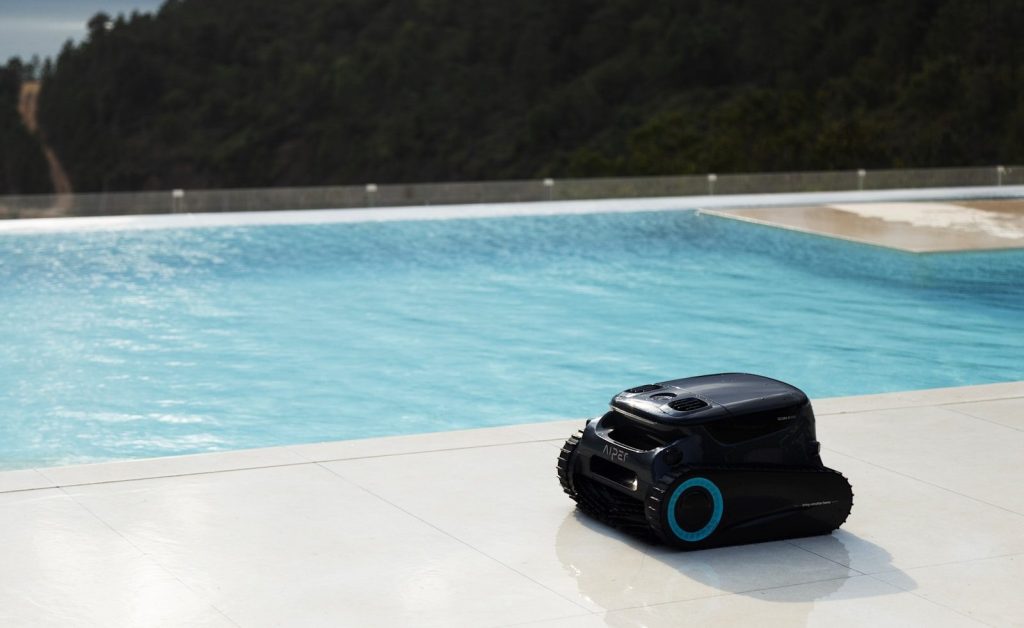 A robotic pool cleaner is next to a pool.