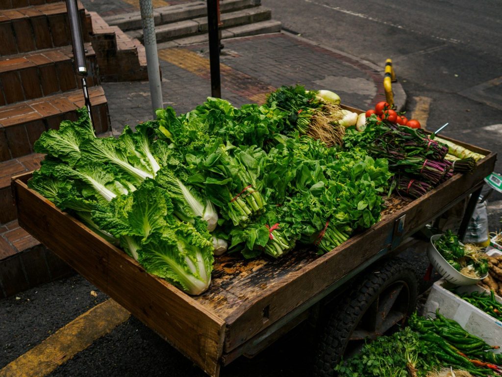 a wooden cart filled with lots of green vegetables