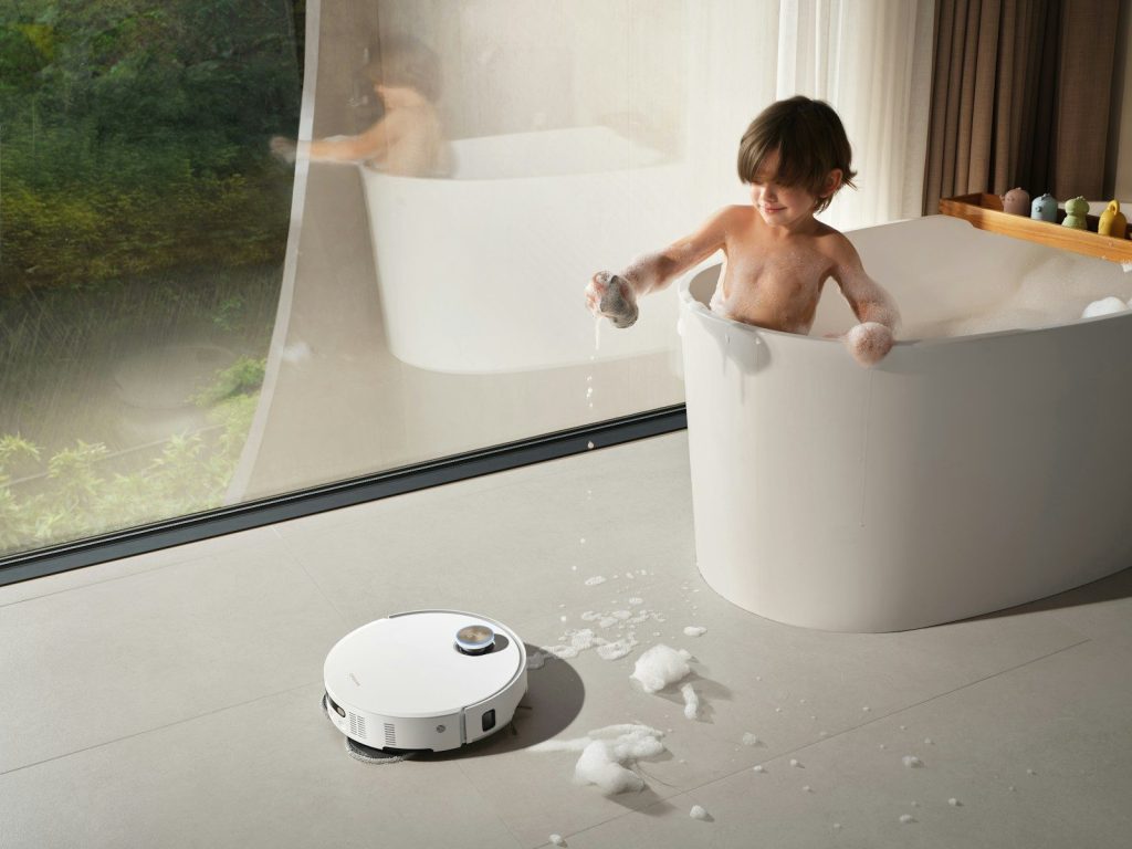 Child playing in bathtub with robot vacuum cleaner
