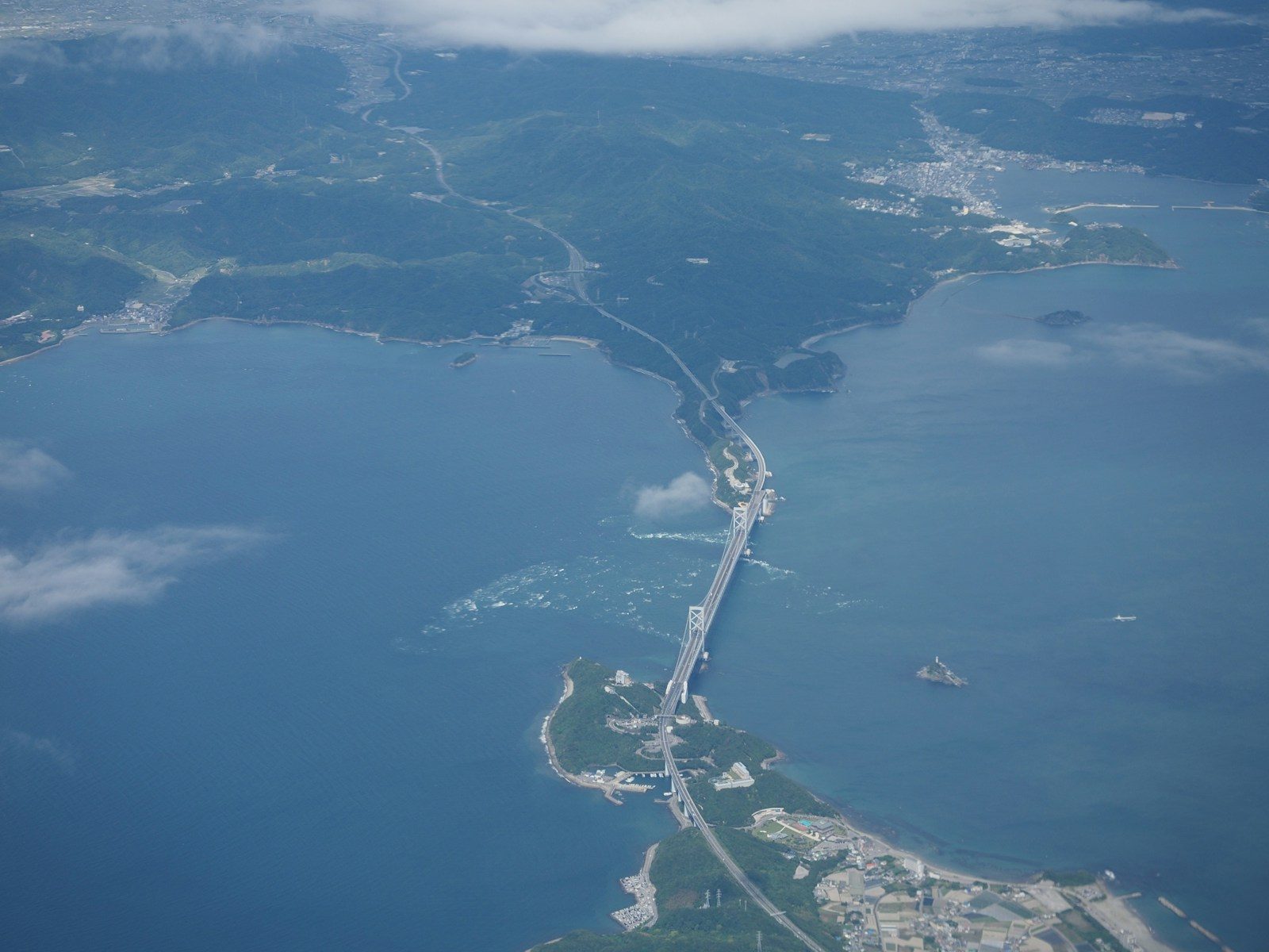 Aerial view of a long bridge over blue water
