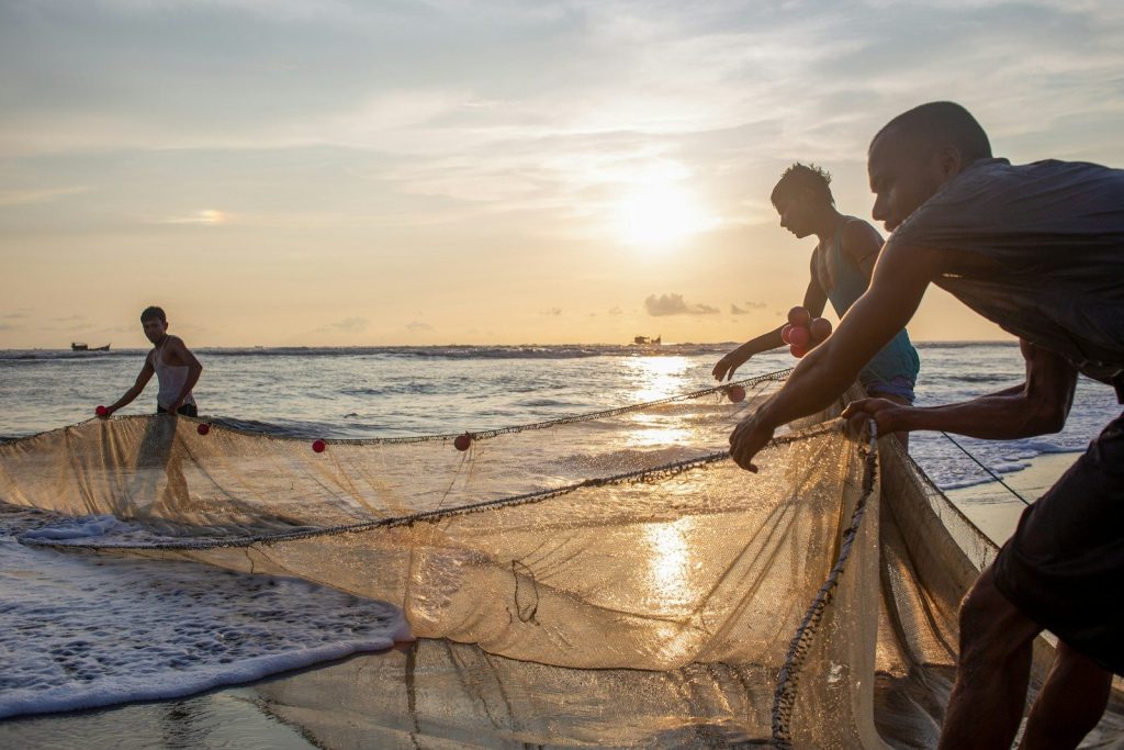 A group of people standing on a beach next to a net